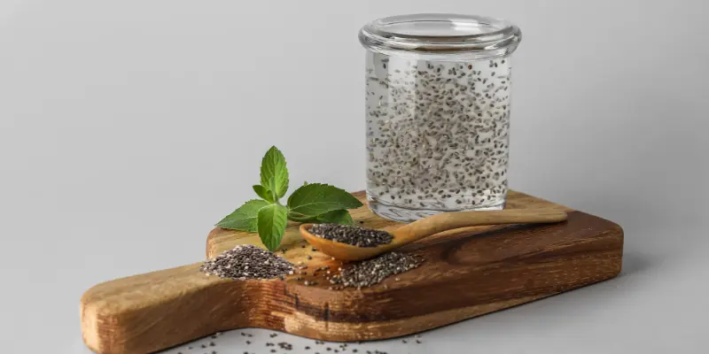 Hydrated chia seeds in a glass with a wooden spoon and fresh mint leaves.